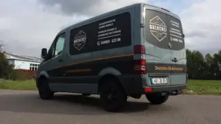Seitenansicht der Fahrzeugbeschriftung für Bäckerei Dorn Fahrzeug der Bäckerei Dorn aus schräger Rückansicht links fotografiert, Beschriftung auf Heck und Seitenfläche deutlich erkennbar – mit Logo und Gestaltung im Bäckerhandwerk-Stil.