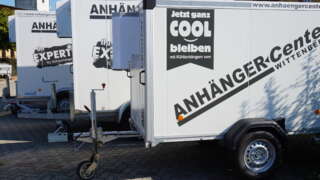 Drei Anhänger stehen nebeneinander und sind jeweils mit auffälliger Werbebeklebung versehen.