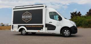 Seitlich aufgenommener Verkaufsstand der Bäckerei Dorn mit elegant bedruckter Seitenfläche und geschlossenem Verkaufstresen – kompakte, mobile Lösung im Markenlook.