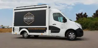 Mobiler Verkaufsstand Bäckerei Dorn – Seitenansicht mit geschlossenem Tresen Seitlich aufgenommener Verkaufsstand der Bäckerei Dorn mit elegant bedruckter Seitenfläche und geschlossenem Verkaufstresen – kompakte, mobile Lösung im Markenlook.