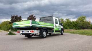 Transporter von hinten gefilmt, vollflächig bedruckt mit auffälliger Fahrzeugbeschriftung im Corporate Design.